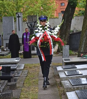 Składanie kwiatów i zapalanie zniczy na cmentarzu pod pomnikiem.