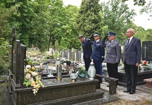 Składanie kwiatów i zapalanie zniczy na cmentarzu na grobach policjantów.