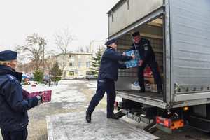 Policjanci wkładają paczki na samochód.