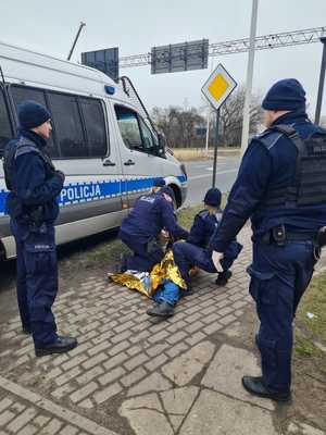 Policjanci udzielają pierwszej pomocy leżącemu na chodniku mężczyźnie