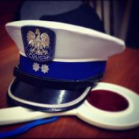 Na stole leży czapka policyjna i tarcza do zatrzymywania pojazdów.