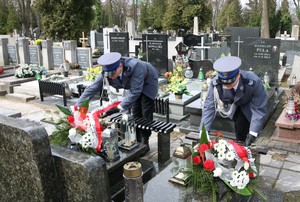 Policjanci składają wiązanki na grobach.