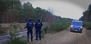 radiowóz na dukcie leśnym, policjanci stoją przy drodze