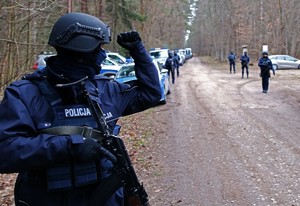las, policjanci w tle z przodu policjant podnosi rękę