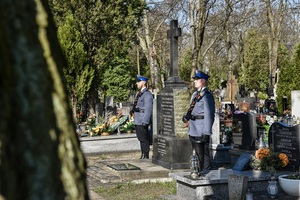Cmentarz, policjanci stoją przed pomnikiem.