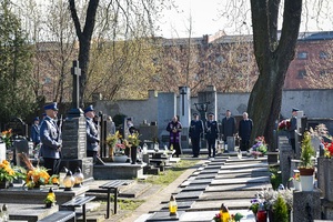 Cmentarz, policjanci stoją przy grobach.