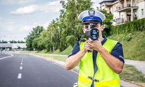 Policjant mierzy prędkość miernikiem prędkości.