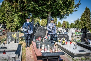 Policjanci stoją przy grobie Jerzego Piekarskiego.