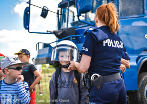 Policjantka zakłada kask dziecku.
