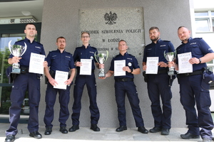Nagrodzeni policjanci z dyplomami i pucharami.