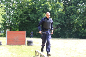 Policjant biegnie po ławeczce z tyłu murek.
