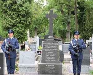 Cmentarz, policjanci stoją na warcie przed grobem.