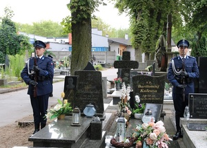 Cmentarz, policjanci stoją na warcie przed grobem.