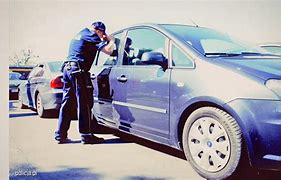 Policjant zagląda do samochodu.