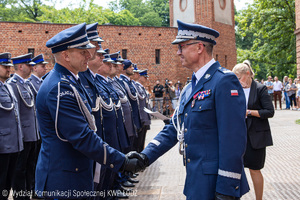 Komendant wojewódzki Policji w Łodzi podaje rękę policjantowi.