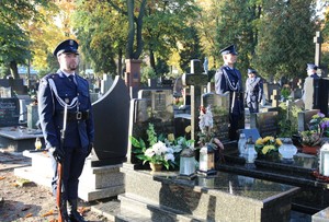 Umundurowani policjanci stoją przy grobie.