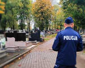 Policjant w mundurze stoi na cmentarzu.