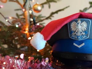 w tle choinka, na pierwszym planie policyjna czapka a na niej czapka Św. Mikołaja.