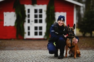 Policjantka kuca, obok pies służbowy.