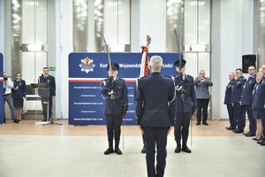 Inspektor Mariusz Krzystyniak Komendant Wojewódzki Policji w Łodzi stoi przed sztandarem.