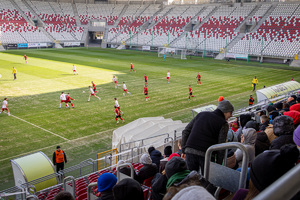 Stadion piłkarski, na trybunach kibice, na murawie rozgrywa się mecz.