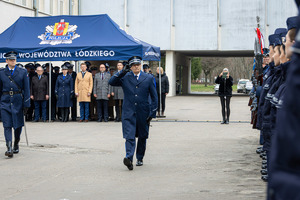 Komendant Wojewódzki Policji w Łodzi przechodzi przed kompanią honorową i oddaje honor, z tyłu pod namiotem kadra garnizonu łódzkiego i zaproszeni goście.