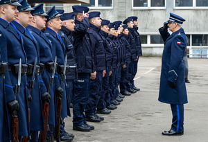 Komendant Wojewódzki Policji w Łodzi stoi na przeciwko nowo przyjętych funkcjonariuszy i oddaje honor.