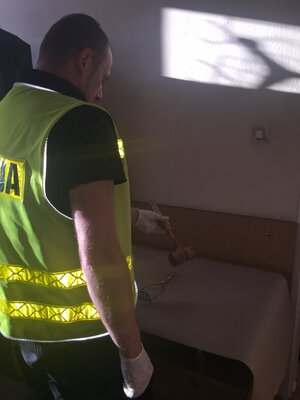 policjant z zabezpieczonym narzędziem zbrodni