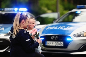 Policjantka odbiera kwiaty od swojego dziecka.