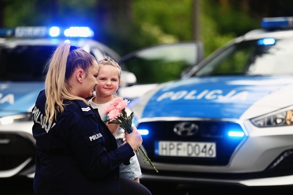 Policjantka odbiera kwiaty od swojego dziecka.