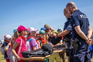 na zdjęciu policjanci prezentują dzieciom elementy  umundurowania wykorzystywane podczas codziennej służby.