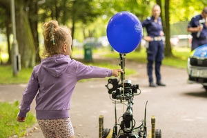 Dziewczynka bierze balonika od robota.
