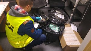 policjant z zabezpieczonymi papierosami