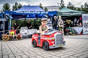 chłopiec w zabawkowym wozie strażackim.