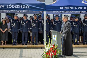Kapelan Wojewódzkiego Duszpasterskiego Ośrodka Policji w Łodzi podczas modlitwy, w tle trybuna honorowa.