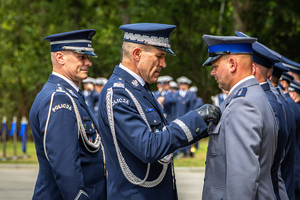 Zastępca Komendanta Głównego przypina medal policjantowi, za nim stoi Komendant Wojewódzki Policji w Łodzi.