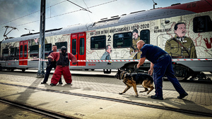 Policjant z psem służbowym podczas pozorowanego ataku w tle wagon pociągu.