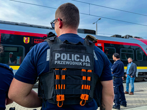 Policjant w kamizelce z napisem przewodnik psa służbowego.