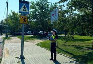 Policjantka stoi przed znakiem &quot;Agatka&quot; robi zapiski w zeszycie.