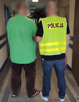 Policjant trzyma zatrzymanego.