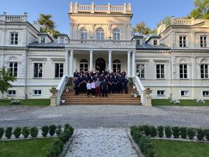 Zdjęcie grupowe osób biorących w szkoleniu przed zamkiem.