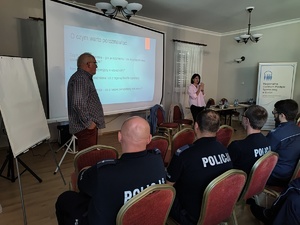 Sala wykładowa, policjanci siedzą na krzesłach, prelegenci prowadzą szkolenie.