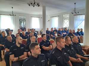 Policjanci siedzą na krzesłach.