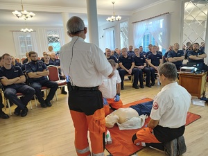 Policjanci siedzą na krzesłach, prelegenci prowadzą wykłady.