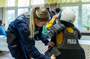 Policjantka ubiera dziecko w strój policyjny.