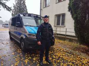 policjant stoi przed radiowozem.