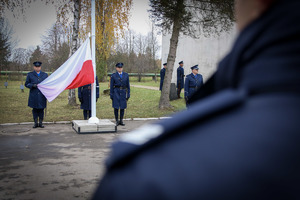 Policjanci trzymają flagę Rzeczypospolitej Polskiej.