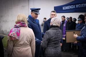 Komendant wręcza certyfikaty rodzinom poległych policjantów.