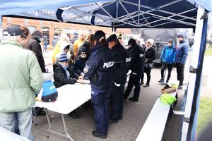 Policjanci podczas pikniku pod namiotem rozmawiają z mieszkańcami.