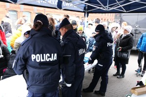 Policjanci podczas pikniku pod namiotem rozmawiają z mieszkańcami.